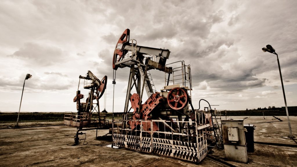 Oil pumps in the fields vintage rusty colour against moody cloudscape. Resource depletion