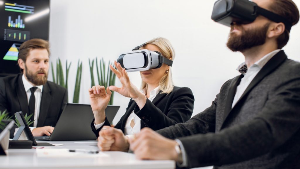 Team of three professional male and female designers or architects, wearing vr headsets, working with new virtual project in modern office