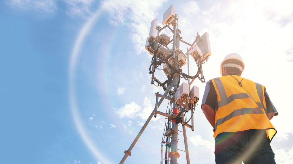 male engineer  with a telecommunication tower that controls cellular electrical installations to inspect and maintain 5G networks.