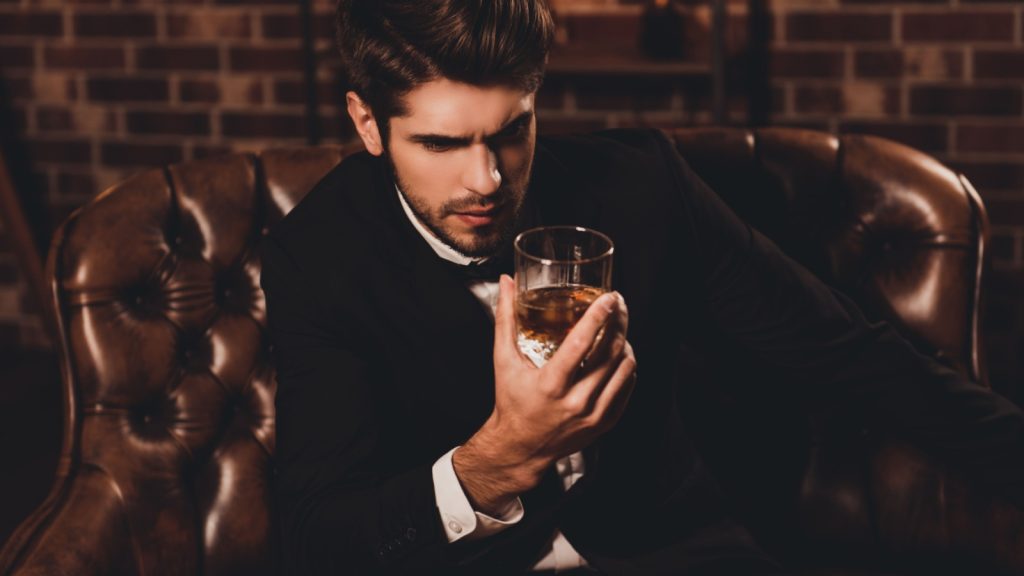 Portrait of handsome young man holding glass of cognac
