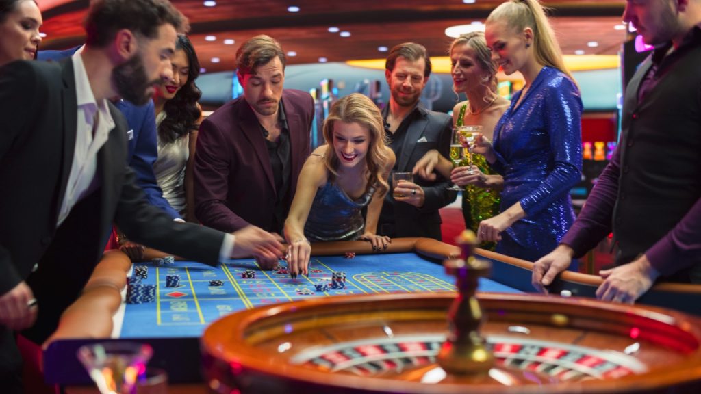 Female and Male Guests Placing Risky Bets while Playing Roulette. Crowd Celebrating a Positive Outcome and Cheering the Winners