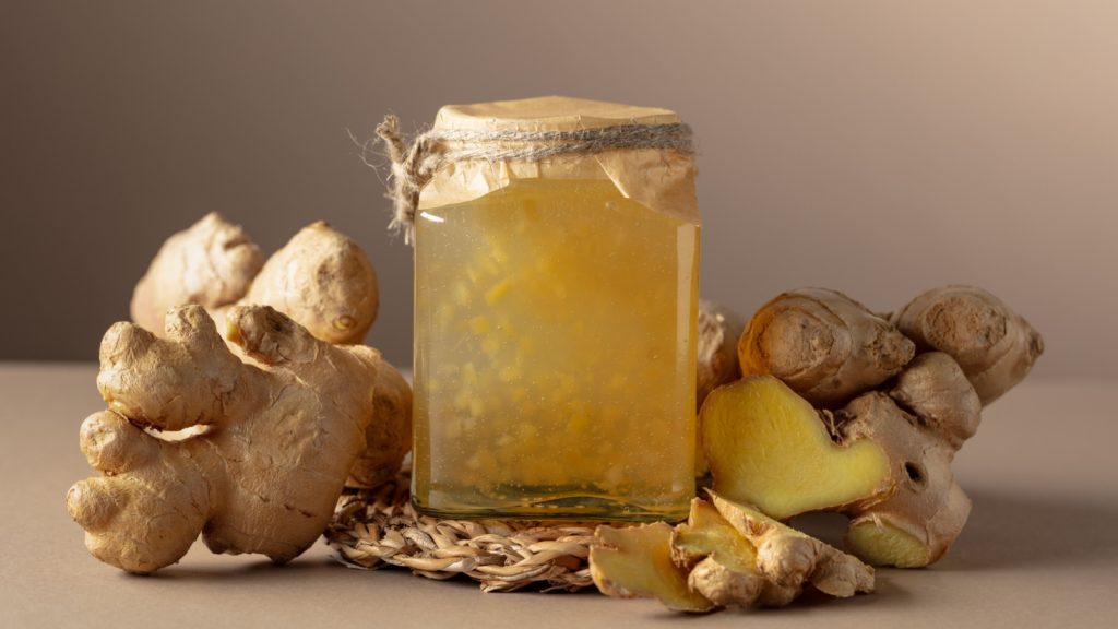 Ginger jam in small square jar and fresh ginger