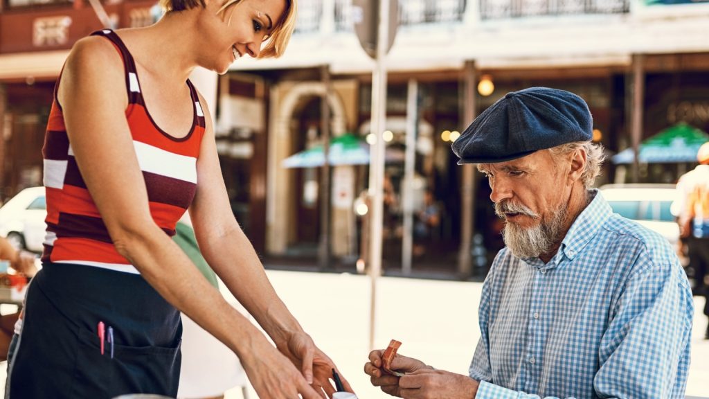 Hes always generous with his tip. Shot of a friendly waitress serving a senior man at a table outside a cafe.