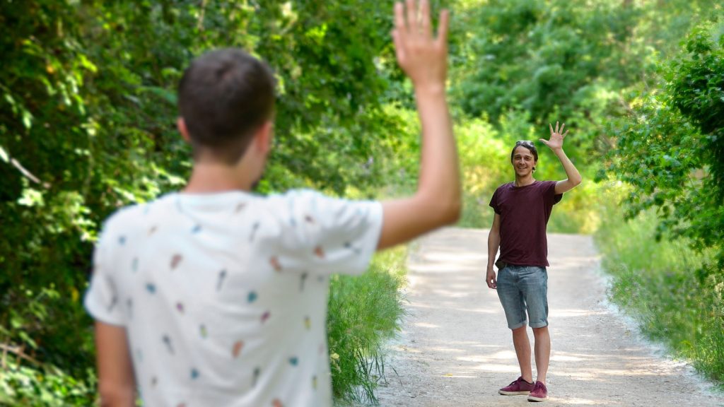 Two-friends-waving-to-each-other-in-nature