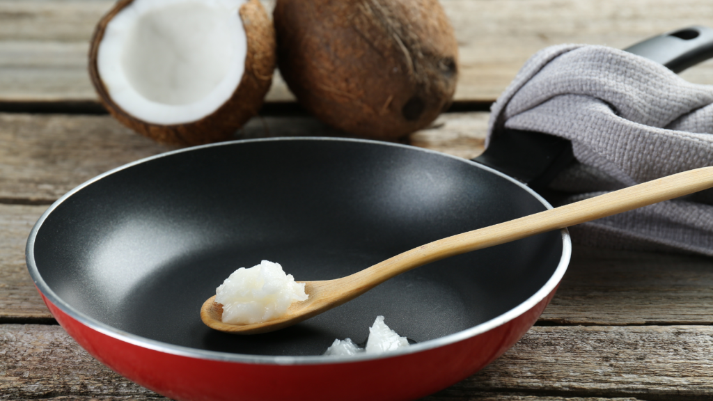 Frying pan with organic coconut cooking oil and spoon on wooden table