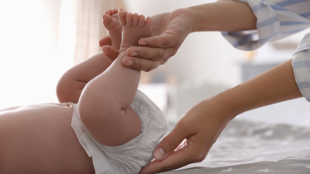 Mother changing her baby's diaper on bed