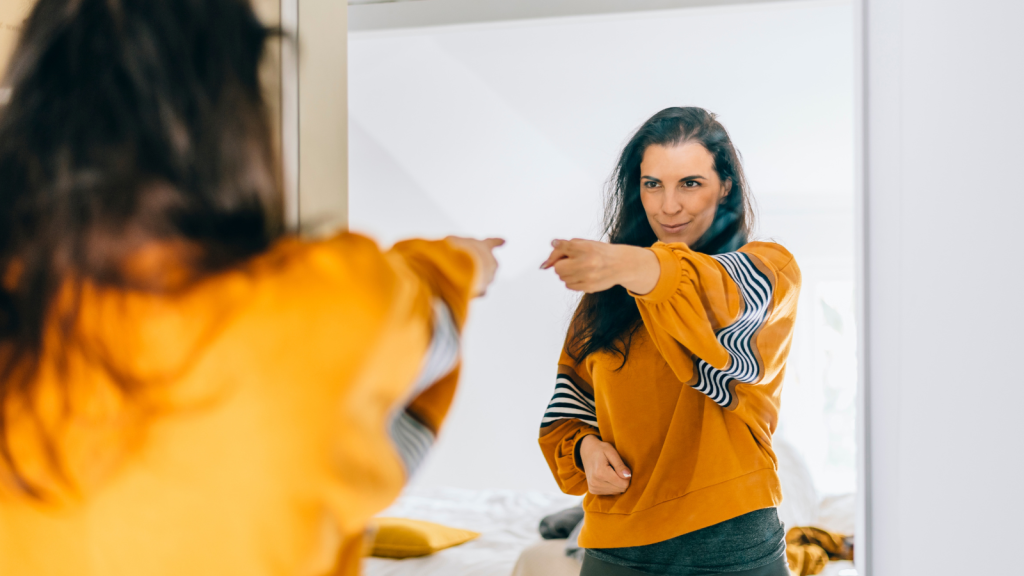 Self confident single woman pointing finger at her reflection in mirror