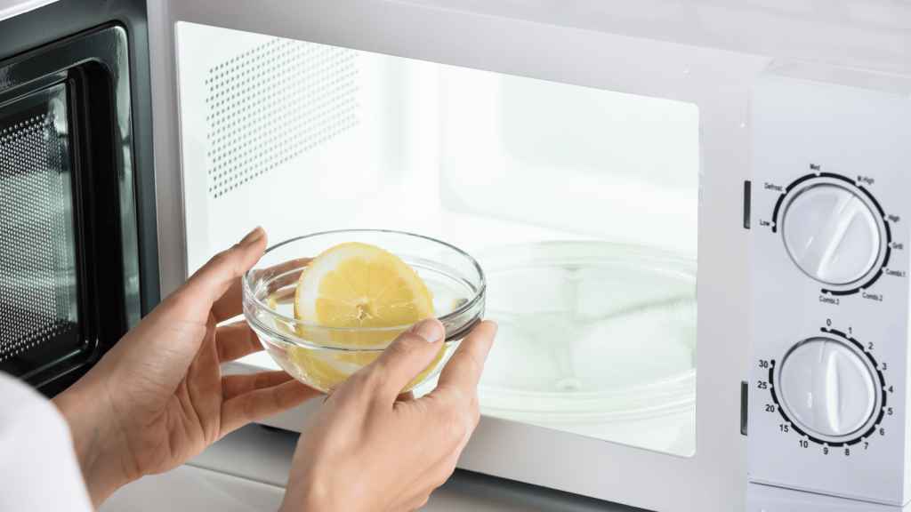 Person putting lemon in a bowl inside a microwave