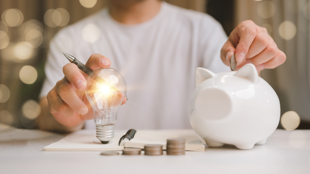 business man hand holding lightbulb and putting coin in to the piggy bank