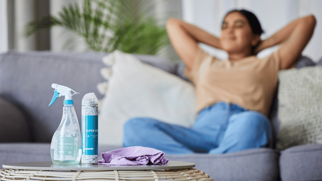 Woman sitting on sofa with cleaning products