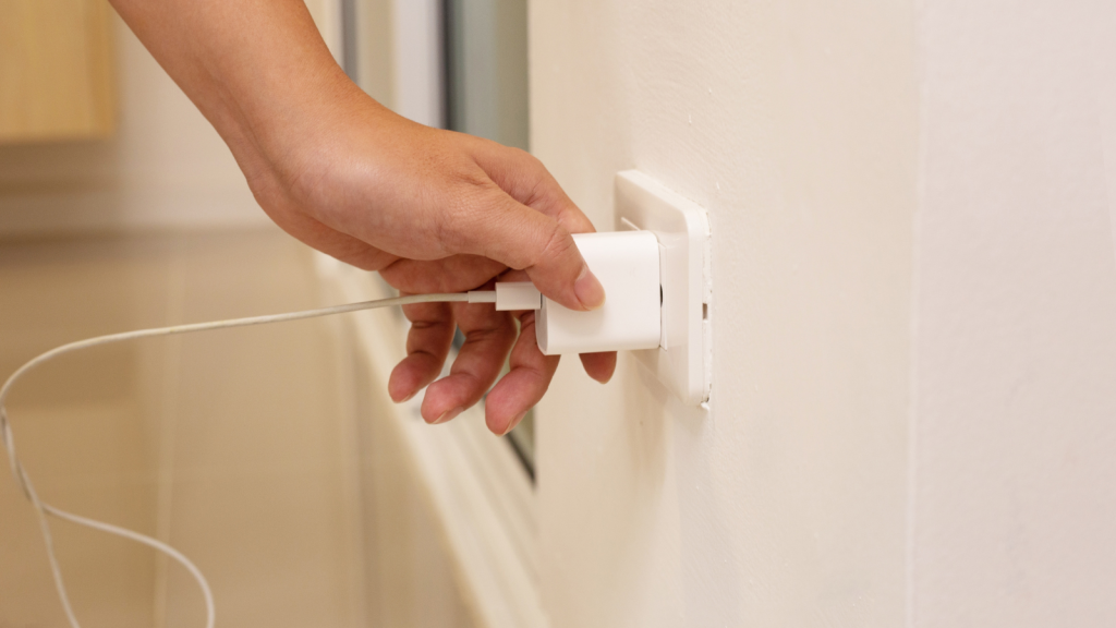 Person unplugging a charger cord on a socket