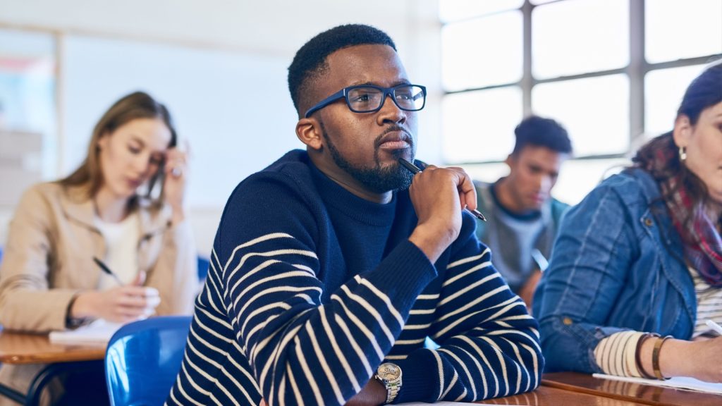 a man listening to a speaker while holding a pen