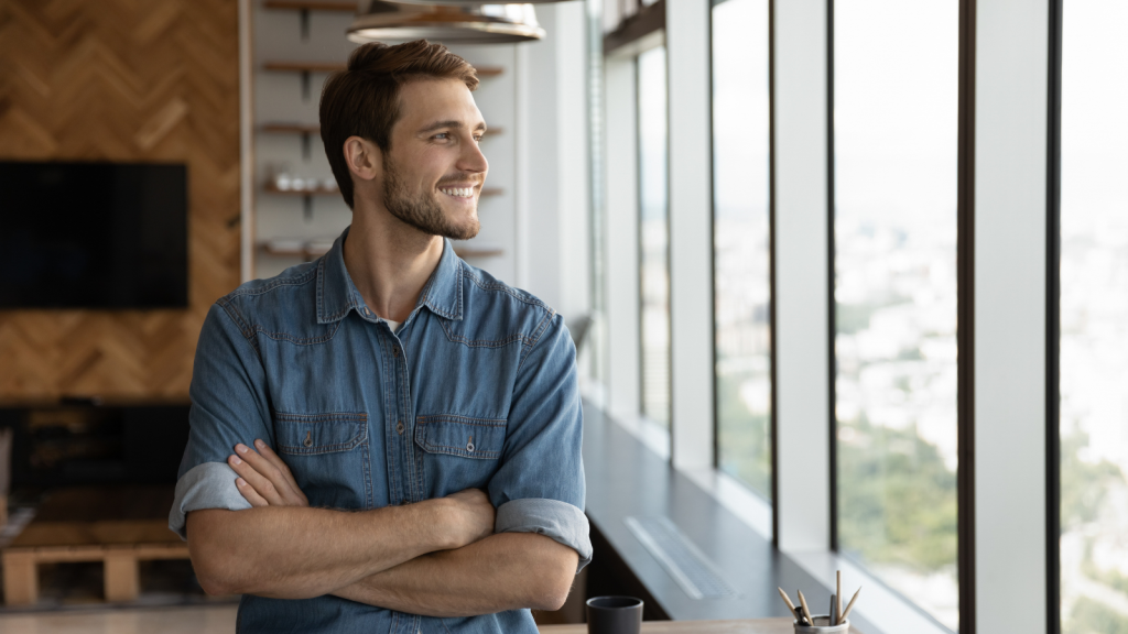 Smiling male employee at workplace looking out the window