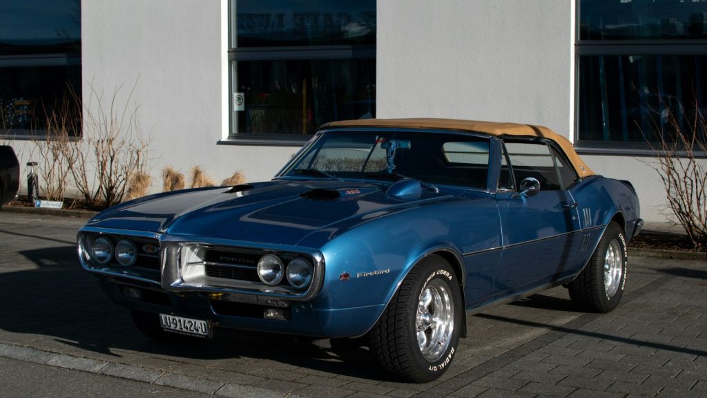 Blue Pontiac Firebird in front of a building