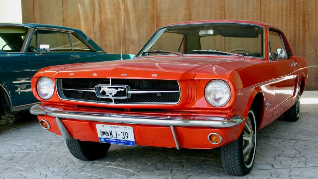 Red mustang parked next to a green mustang