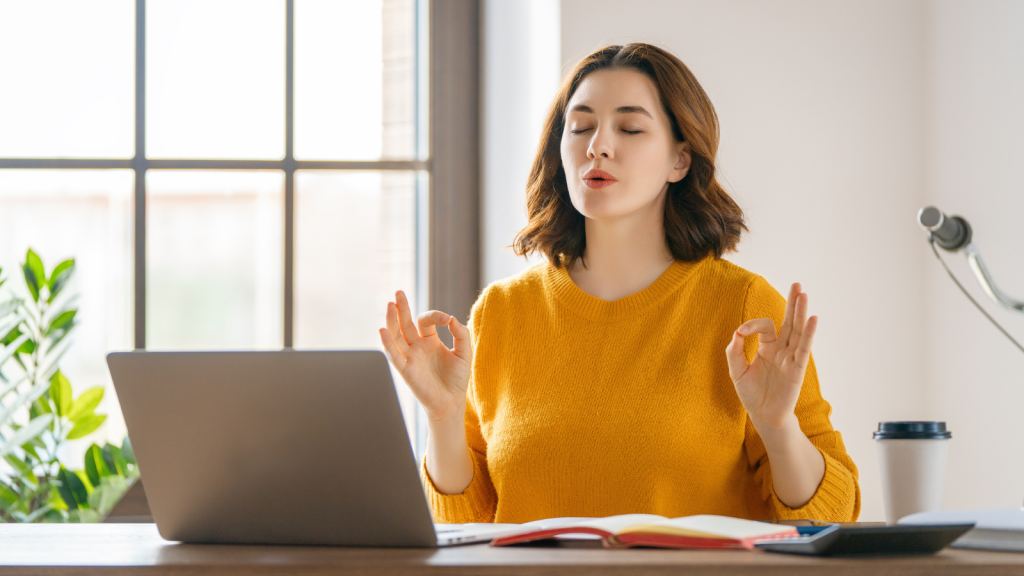 Woman working in the office and practicing deep breathing for calm and concentration