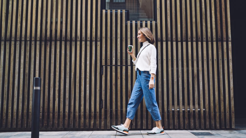 middle aged female in jeans and sneakers strolling along street