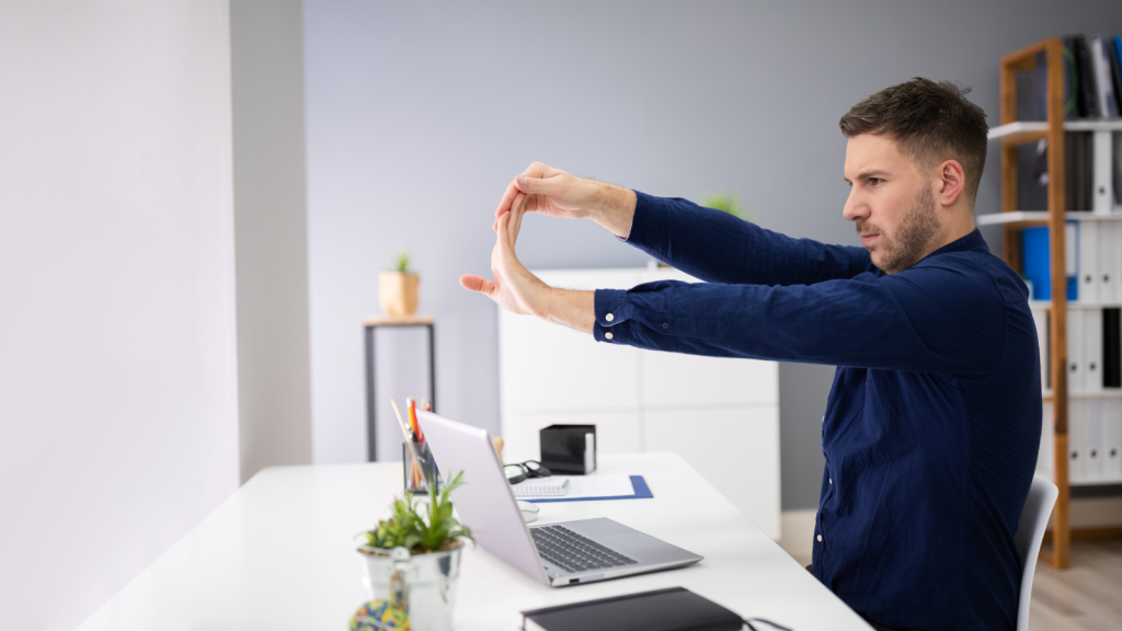 Man doing Wrist and Finger Stretches in his office desk