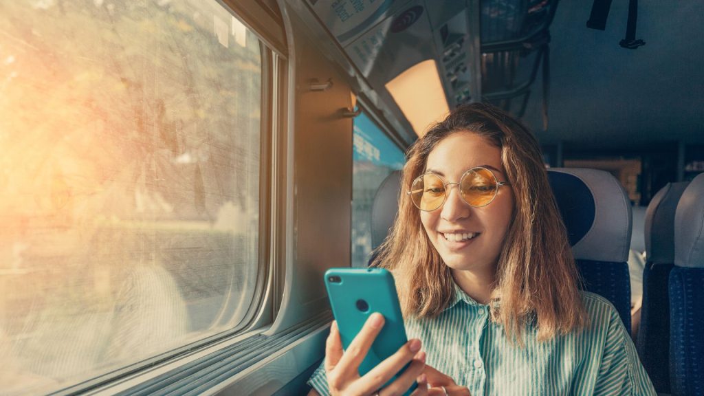 A girl with a smartphone travelling by a train