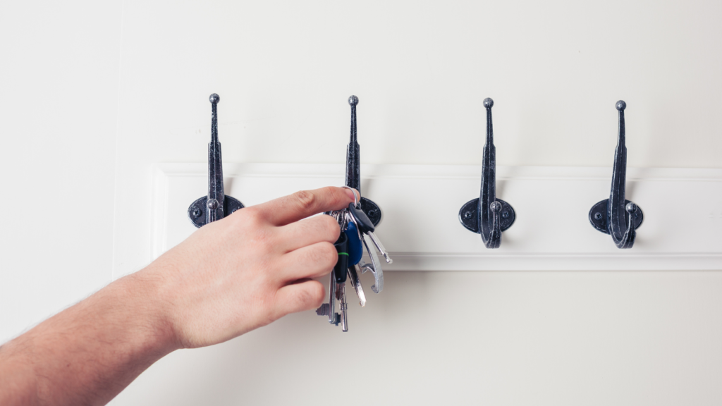 A male hand is hanging keys on a hook