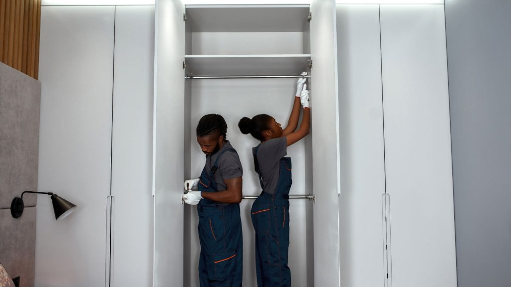 A man and woman installing closet rods