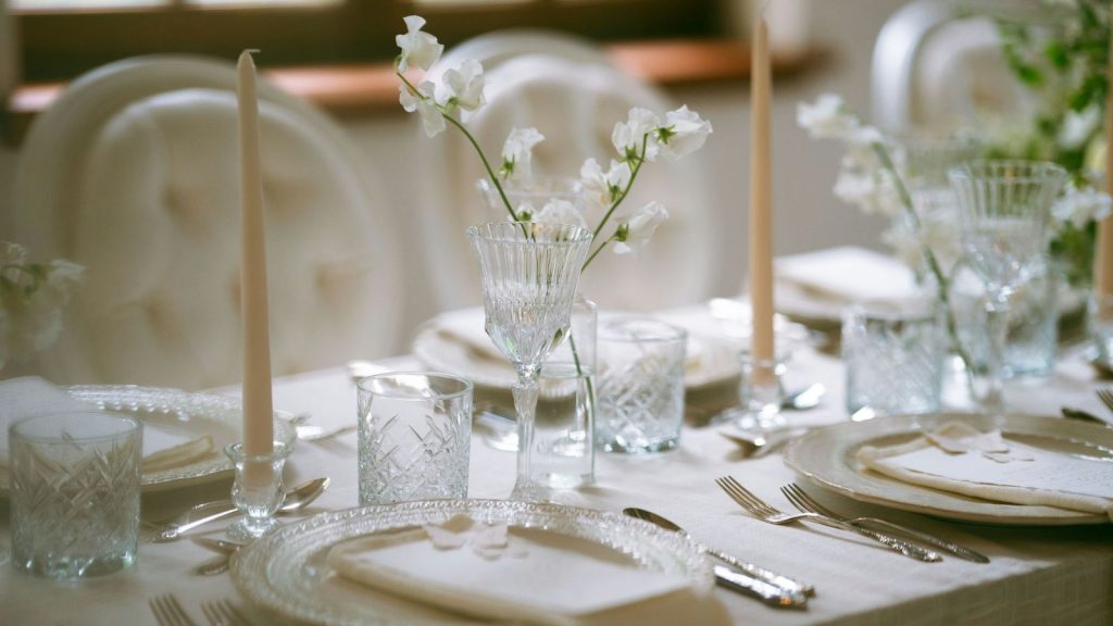 A table set for a wedding dinner with flowers and fancy dinnerware