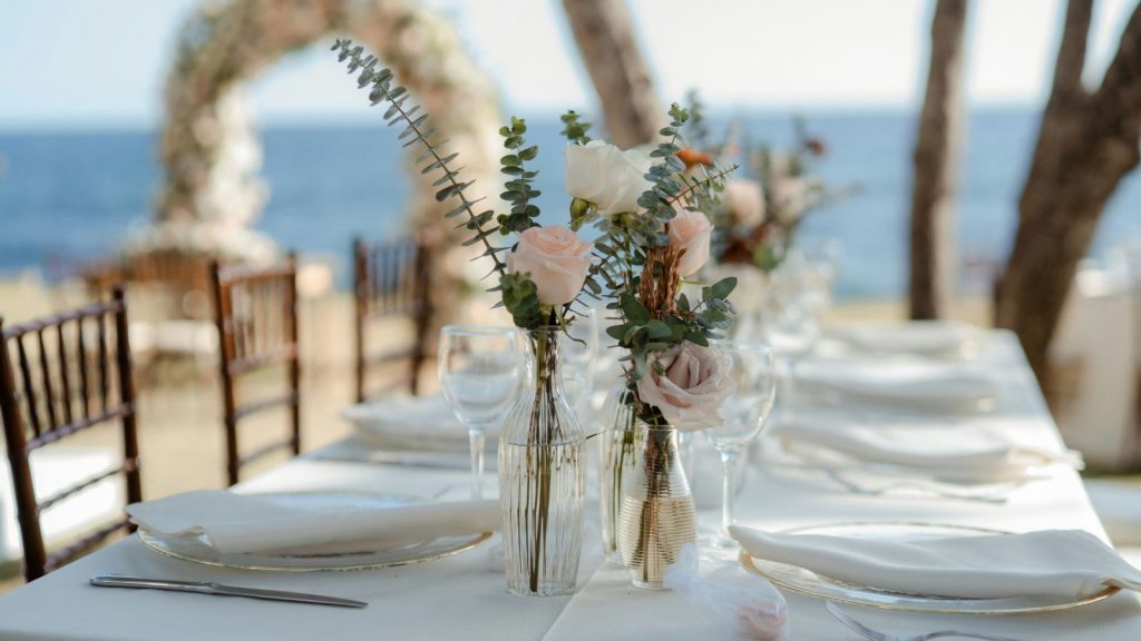 A table set for a wedding with flowers at a beach front