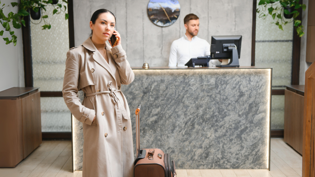 Businesswoman with luggage in modern hotel lobby using smartphone