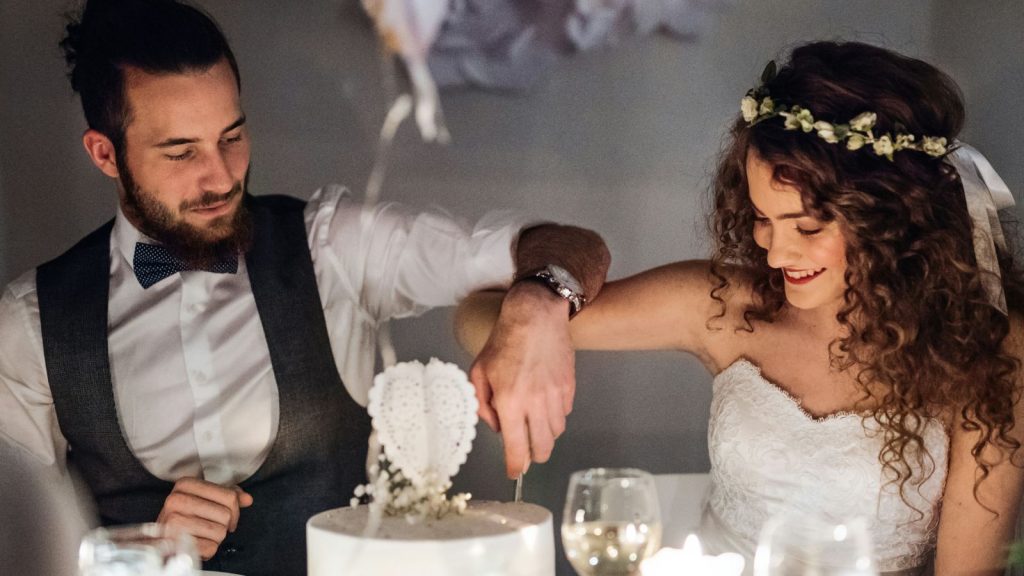 Couple sitting at a table on a wedding cutting a cake