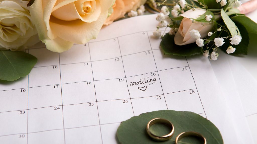 Creative flat lay of two golden rings with date choosing on paper calendar