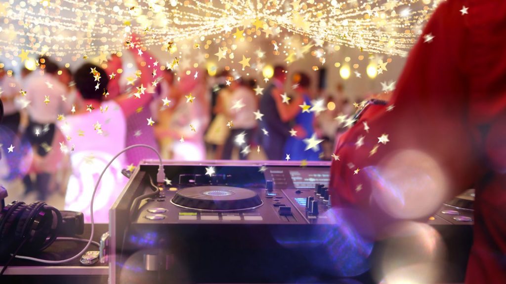 Dancing guests during party or wedding celebration with male DJ