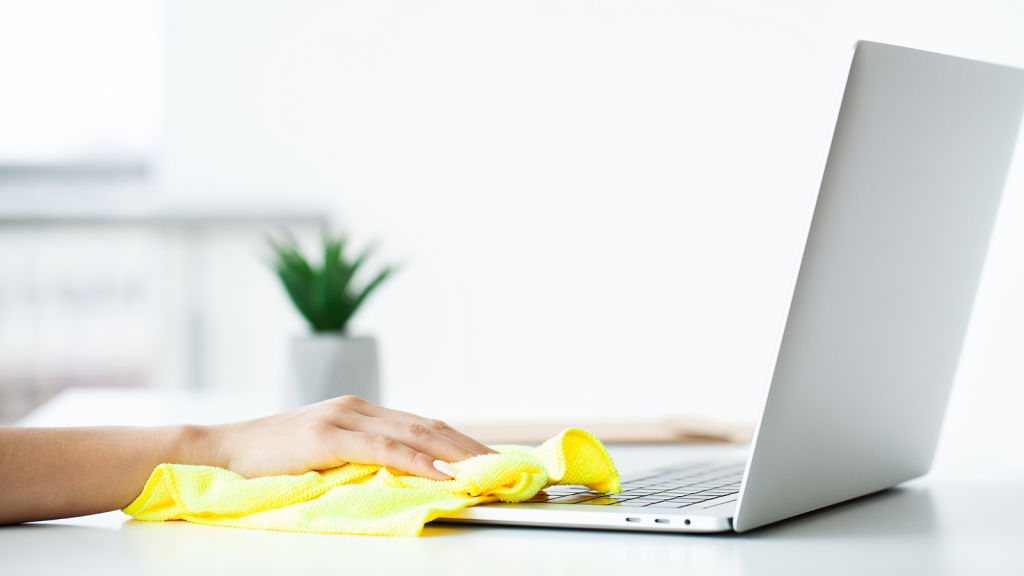 A hand cleaning laptop on work desk table