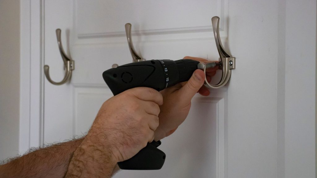 Image of a hand of a man installing hook at the back of closet door