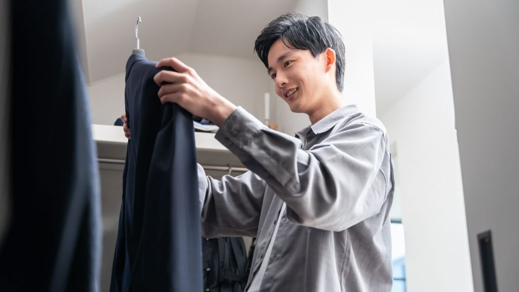 Image of a man in a neatly organized wardrobe featuring a capsule wardrobe collection