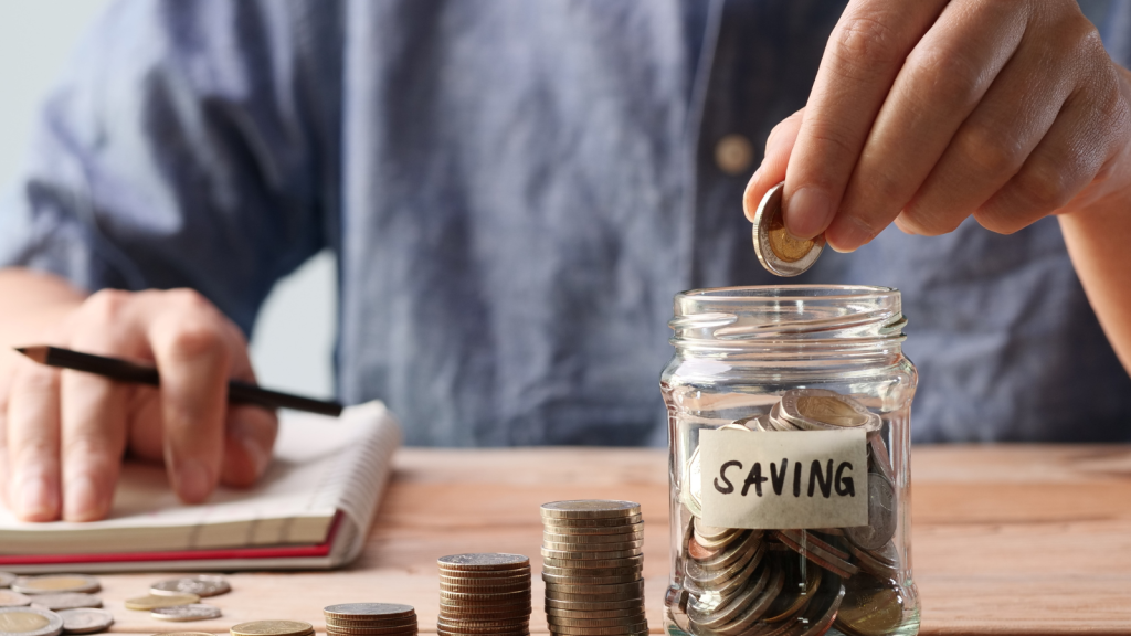 Man hand putting coins in a glass jar