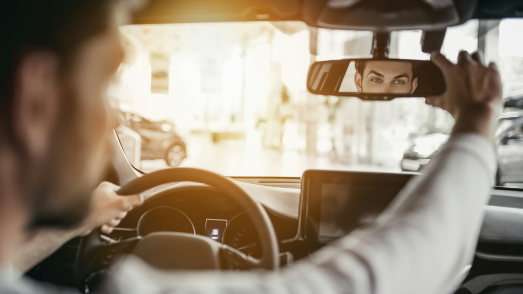 Man inside a vehicle holding the rear view mirror