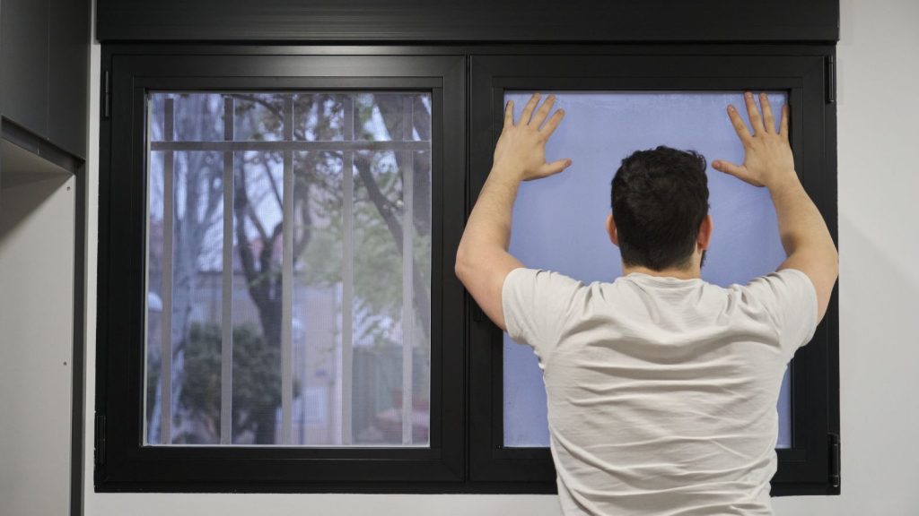 Man installing frosted window vinyl on wet window glass