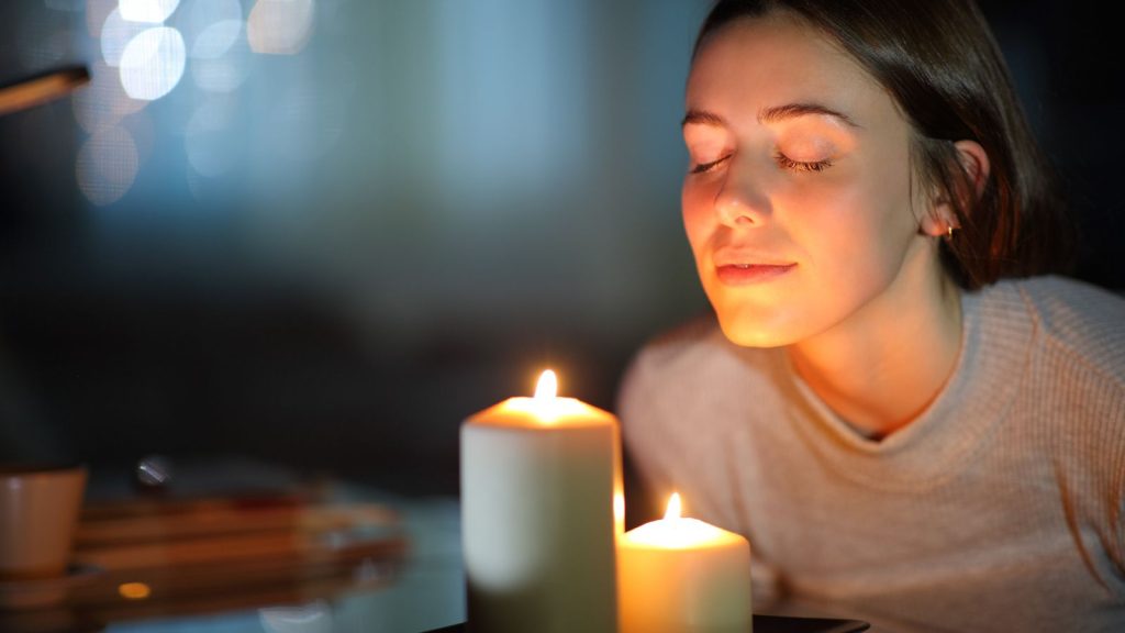 Relaxed woman smelling a lighted scented candle