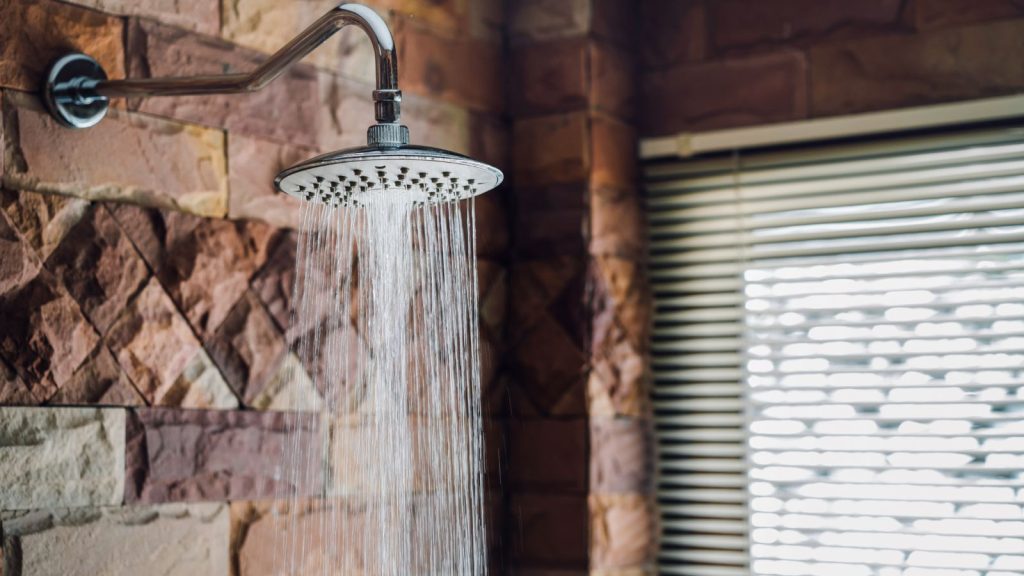 Shower in bathroom flowing water drop to the floor at modern home of brick style near window