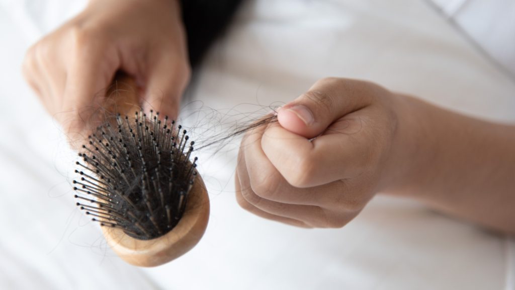 A close-up of a dirty hairbrush with tangled hair and debris.