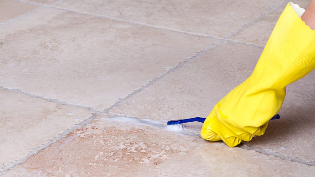 A person scrubbing grout lines with a toothbrush.