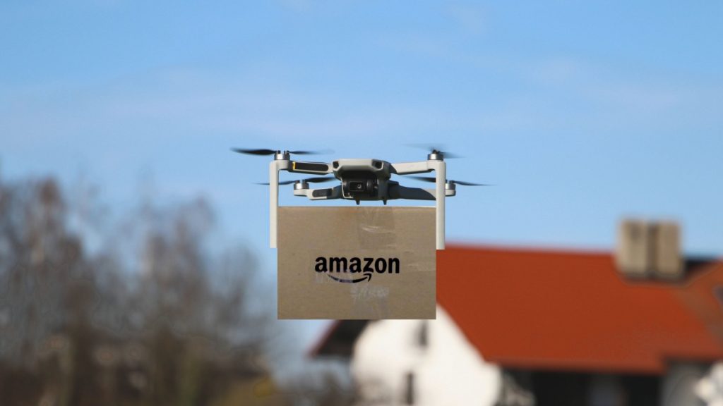 selective focus of drone delivering parcel with amazon logo on cardboard