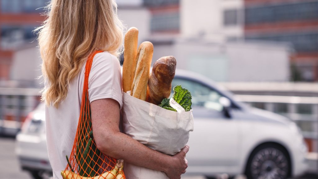 a woman carrying grocery bags to her house
