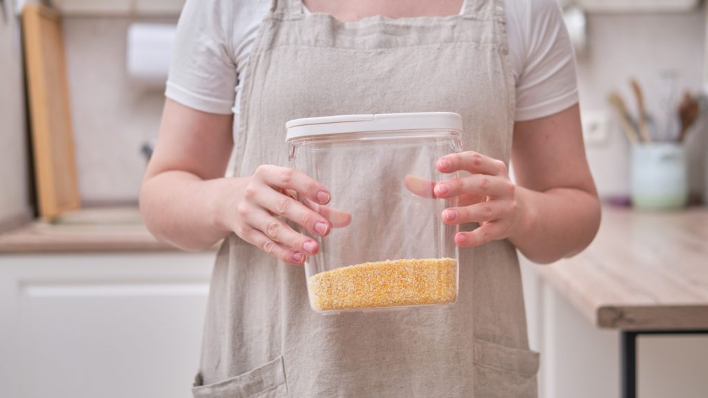 a woman is holding a plastic container with cereals.