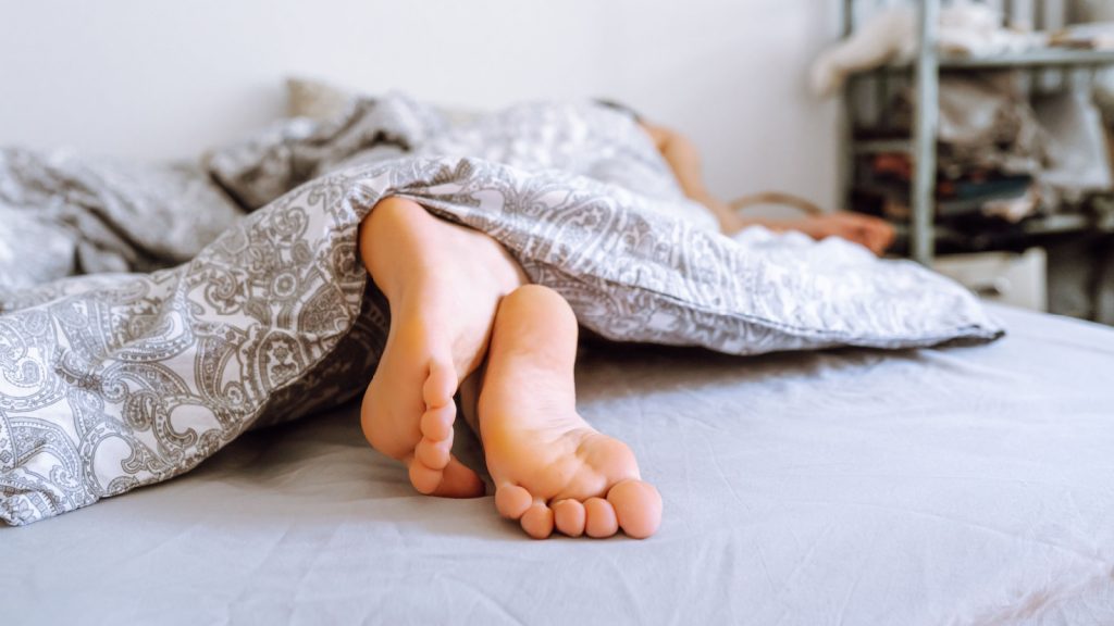 feet of sleeping woman peaking out of duvet
