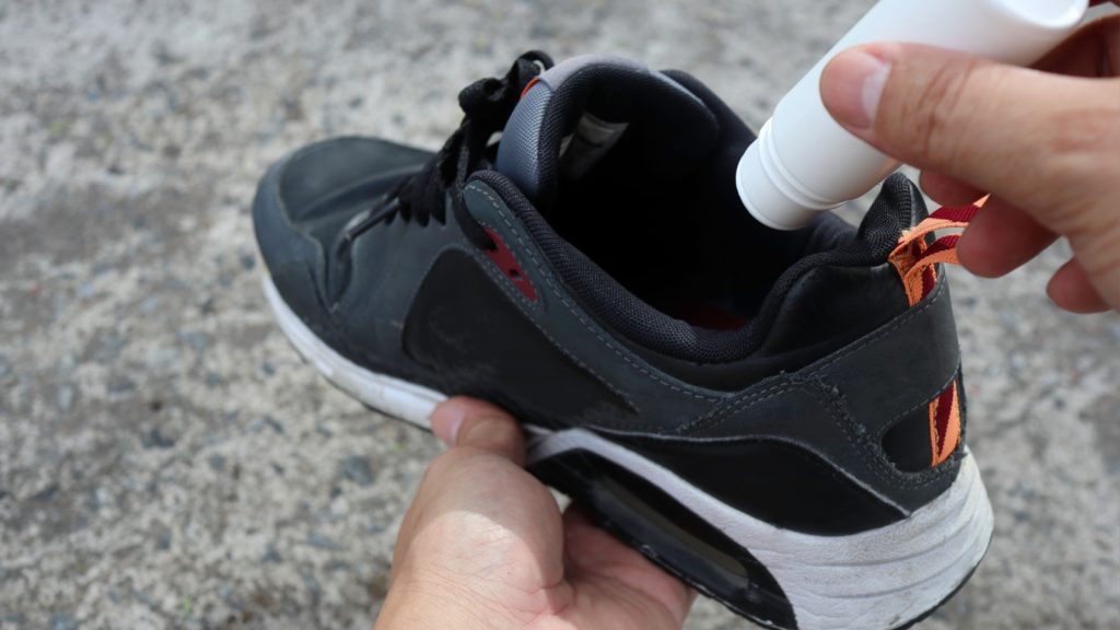 A person sprinkling baking soda inside a shoe to freshen it up.