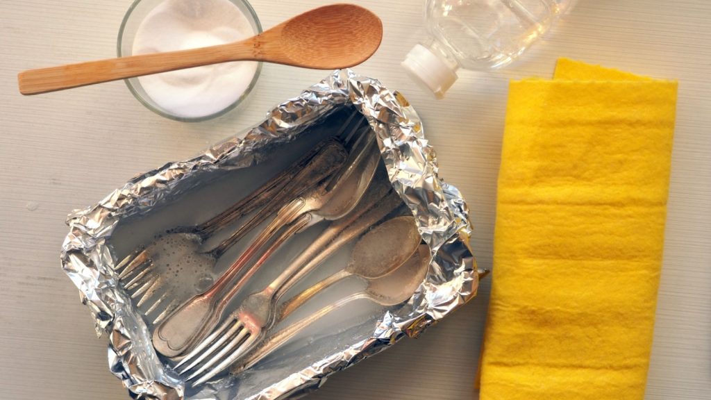 Silverware being cleaned using baking soda for a polished finish.