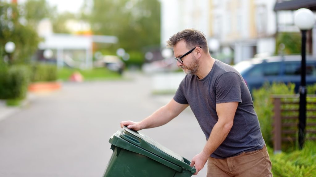 a man putting out trash bin
