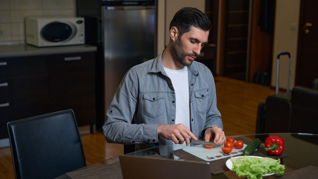 a man cuts tomato for a vegetable salad
