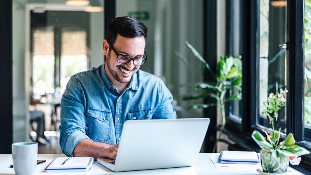 a happy young entrepreneur working on his laptop